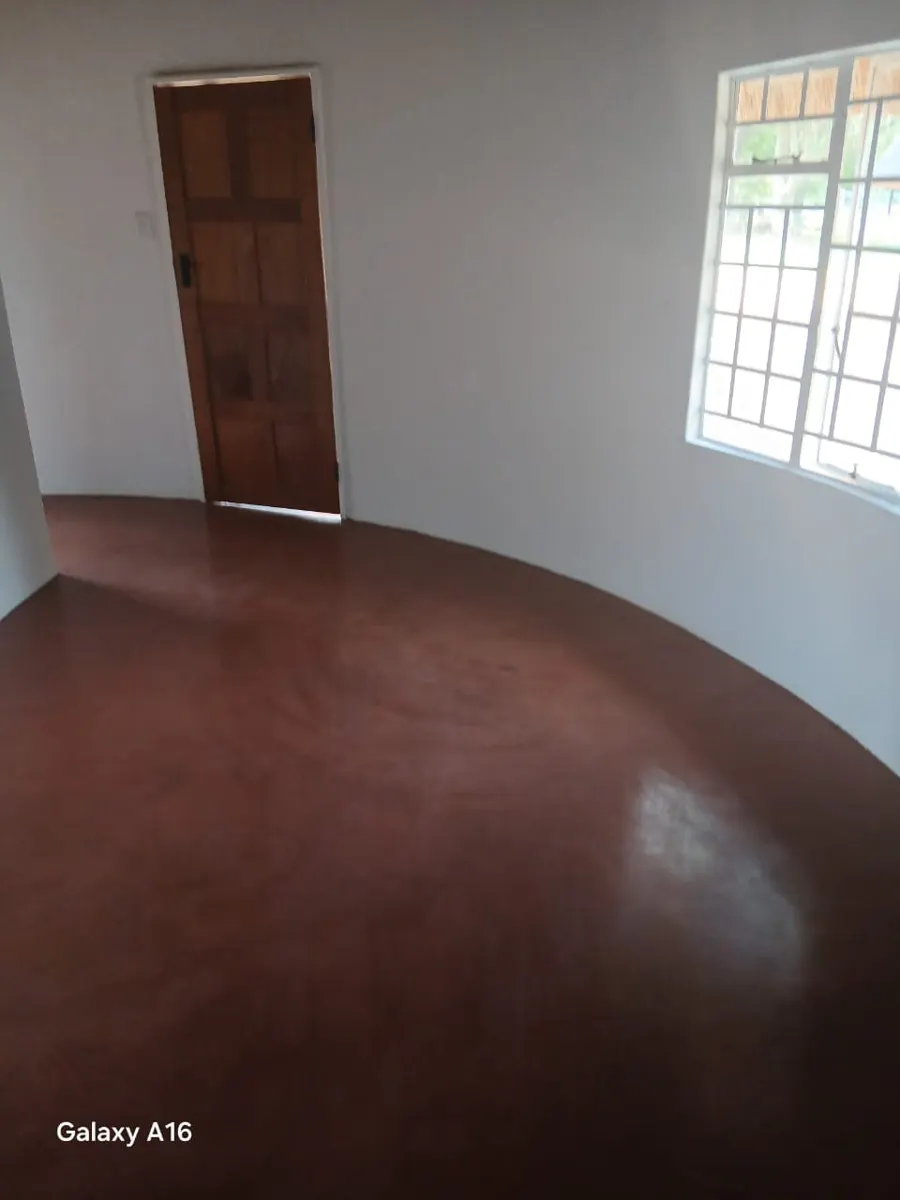 Rondavel bedroom with polished screed floor and timber door